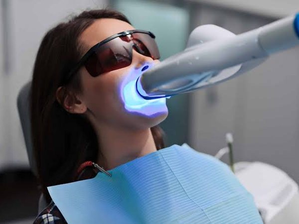 Home Patient receiving a teeth whitening treatment with a blue LED light and protective glasses at C.Metric dental clinic in Dbayeh
